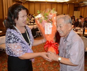３４年間、宮古の教育発展に貢献した平良さん（手前右）に花束が贈呈され、叙勲受章と米寿を盛大に祝った＝１日、市内ホテル