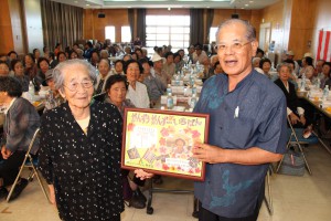 饒平名副会長（右）から最高齢表彰を受ける砂川さん＝30日、城辺社会福祉センター