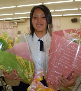 花束を手に大学でも競技を続け、東京オリンピック出場を目指したいと話す福里さん＝１９日、市内レストラン