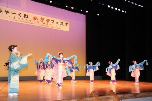 星野京子さん（左）の歌に合わせ創作日本舞踊を踊る鏡原学区婦人会＝２２日、マティダ市民劇場