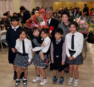 孫たちから花束の贈呈を受けて笑顔を見せる真壁恵修さん（後列中央）＝１６日、市内レストラン