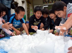 初めての雪に触れて飛び切りの笑顔を見せる子供たち＝５日、池間添児童館