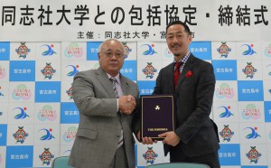 下地市長と（左）と村田学長が互いに署名し包括協定を締結した＝２６日、市役所平良庁舎