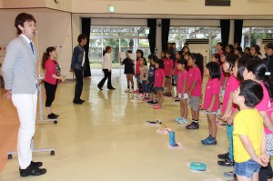 渡久山さん（左）ら役者陣の助言を受けながら母音で歌う練習をする合唱団の子供たち＝１日、市中央公民館