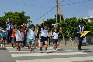 手を上げて横断歩道を渡る児童ら＝１４日、狩俣小学校前