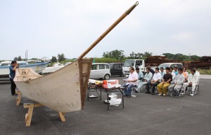 「平成の五勇士」と期成会のメンバーらが参加して行われたサバニに魂を入れる儀式。手前が復元されたサバニ＝２７日、久松漁港