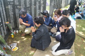 初めて「平和の礎」を訪ね父親の名前に手を合わせる新里康子さん（手前左）ら＝２３日、糸満市の「平和の礎」