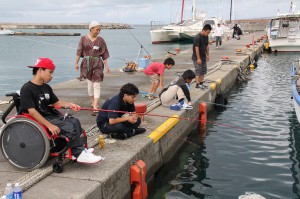 自分の釣り竿に当たりが来るのを待つ参加者たち＝１８日、荷川取漁港