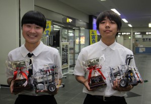 ＷＲＯｊａｐａｎ沖縄ロボット大会で優勝した赤嶺さんと内間君。２人が手にしているのは大会に使用したマシンと優勝カップ＝１６日、宮古空港
