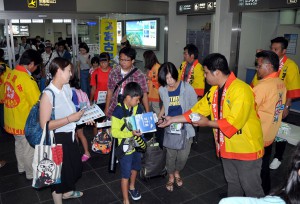 東京から訪れた観光客を歓迎する市職員ら。宮古島をアピールした＝２５日、宮古空港