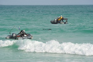 捜索する市消防本部と海上保安署のゴムボート。中央は捜索するダイバー＝１０日午後５時１０分すぎ、伊良部島の渡口の浜