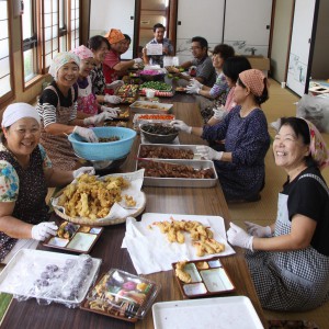 手作りの料理を弁当箱に詰める女性たち＝１７日、下地公民館