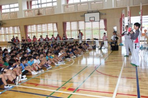 神里さんと照屋さんから説明を聞く児童たち＝１６日、久松小学校体育館