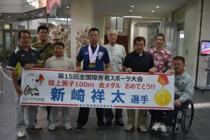 金メダルと銀メダルを胸に記念撮影に応じる新崎さん（中央）と池間会長（右から４人目）ら＝２７日、宮古空港