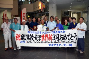 マスターズ陸上３冠を達成した亀濱敏夫さん（中央）の快挙を祝おうと多くの関係者が出迎えに訪れた＝４日、宮古空港