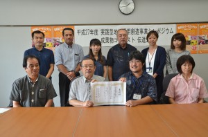 成果物コンテストのものづくり部門１位の表彰状が松嶋部長（手前左から３人目）から長濱会長（同２人目）に伝達された＝１６日、市役所平良庁舎