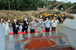 宮糖の安村社長（左から４人目）ら関係者がキビの束を投げ入れ今期操業をスタートさせた＝１４日、宮古製糖伊良部工場