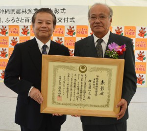 島田農水部長（左）から表彰状を贈られた伊志嶺さん＝６日、那覇市の奥武山運動公園