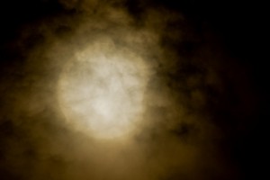 雲間から一瞬顔を出した太陽は右側の一部が欠けていた＝９日午前９時３３分、カママ嶺公園から