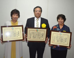 個人功労で表彰された久貝さん（左）と本村さん（右）、個人貢献の伊計さん（中央）＝１１日、県庁講堂