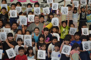 豊ノ島関（中央）と一緒に記念撮影する子供たち＝２５日、狩俣公民館