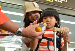 東京や大阪からの観光客に冷たいマンゴージュースをプレゼントした＝１５日、宮古空港