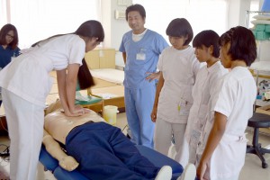 斉藤医師（右から４人目）から指導を受け心臓マッサージを体験する生徒＝２３日、宮古島徳洲会病院