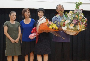 部長就任を祝って花束を贈呈された島尻勝広氏（右端）と夫人の博美さん（右から２人目）＝２５日、浦添市