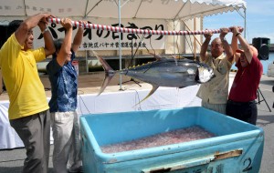 マグロを持ち上げてパヤオの日まつりを宣言する下地市長（右）ら関係者＝１３日、佐良浜漁港