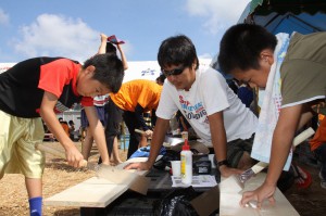 のこぎりで材料の木材を切る子供たち＝７月３１日、メイクマン宮古店