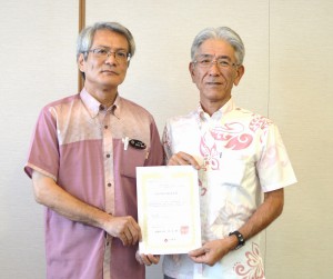 商工労働部の屋比久部長（左）から計画承認書を受けた長濱さん＝２０日、県庁