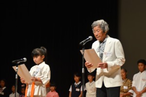 最高齢の来間さん（右）と最年少の宮里さんが開会宣言を読み上げた＝１８日、宜野湾市の沖縄コンベンションセンター劇場棟