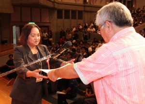 石川会長（右）から功労者表彰を受け取る本村さん＝２７日、マティダ市民劇場