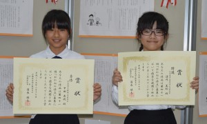 「おかねの作文」で特選を受賞した湧川さん（右）と秀作の中田さん＝１７日、県庁県民ホール