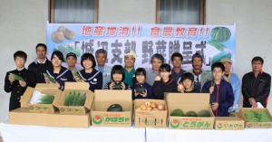 城辺の児童生徒（前列）に地元産野菜が贈られた贈呈式＝２３日、城辺公民館前