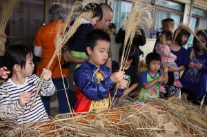 ススキの穂を使った昔ながらのほうき作りに挑戦する子供たち＝１９日、東川根自治会館