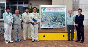 市へ津波避難マップを贈呈した建設３社の社員ら（左）＝１０日、平良港ターミナルビル裏