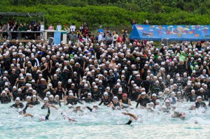 １５５２人が出場。最初の種目スイムで水しぶきを上げて力泳する選手＝２３日、与那覇前浜