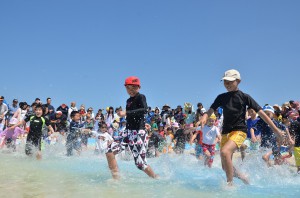 冷たい風と温かい太陽の光を受けてビーチに設置された簡易プールで初泳ぎを楽しむ子供たち＝２日、与那覇前浜ビーチ