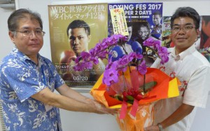 島袋支店長（右）から世界チャンピオン誕生を祝う花が山城教頭に手渡された＝２３日、宮古工業高校