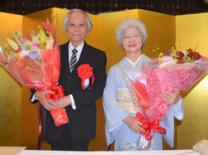 叙勲祝賀会で祝福される西里さんと妻カツ子さん＝１８日、那覇市のマリエールオークパイン