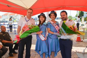 ミス宮古島（中央２人）からモナス副船長（写真右）らに歓迎の花束が贈呈された＝９日、平良港ターミナルビル前