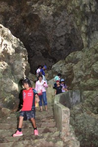 自然洞窟の中に湧き水をたたえるあま井の石段を降りる参加者＝１２日、城辺友利地区
