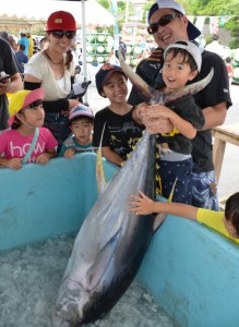 大物キハダマグロを掲げ笑顔を見せる子供たち＝１１日、佐良浜漁港