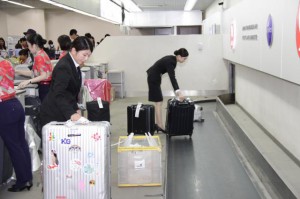 カウンター内で乗客の機内預け入れ荷物を受け取り、コンベヤーへ乗せる田村さん（左手前）と友田さん（右）＝２２日、宮古空港
