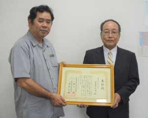 砂川靖保健医療部長（左）から表彰状を伝達された元宮古病院長の安谷屋正明さん＝１０日、県庁