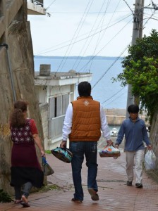 旧正月を重んじる佐良浜地区では、午前中から重箱に入れたごちそうを持って歩く住民の姿が見られた＝16日、伊良部の佐良浜
