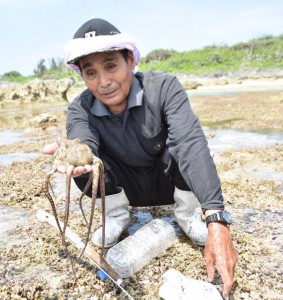 タコ捕り名人の喜久川さんは手作り銛でタコを捕獲した＝18日、下地島のサンゴ礁