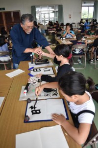 池田会長が指導し、子供たちは伸び伸びと書いた＝２１日、下地農村環境改善センター　