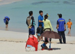 ブルーの服を着た参加者らが観光客らにチラシを配布した＝２日、伊良部渡口の浜